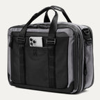 Slanted Front view of the Travelpro® Altitude™ Full Expansion Brief in Falcon Grey, featuring a smartphone in the front pocket, dual top handles, adjustable straps, and multiple zippered compartments.
