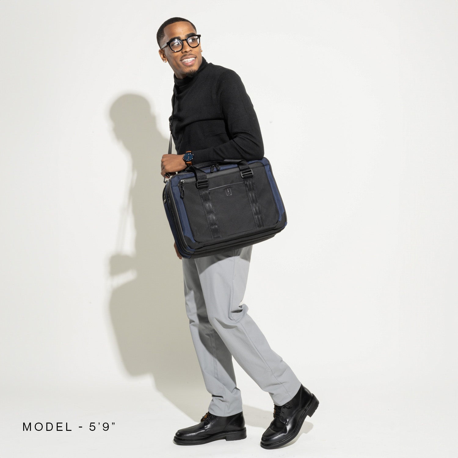 "Model (5'9") carrying a Travelpro® Altitude™ Full Expansion Brief in Aviator Navy over the shoulder while walking."
