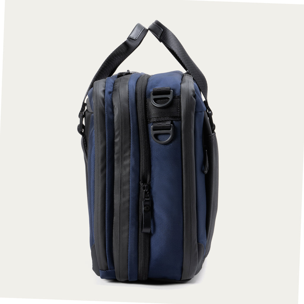 Side view of the Travelpro® Altitude™ Full Expansion Brief in Aviator Navy, highlighting its dual zippered compartments and attachment points for a shoulder strap.
