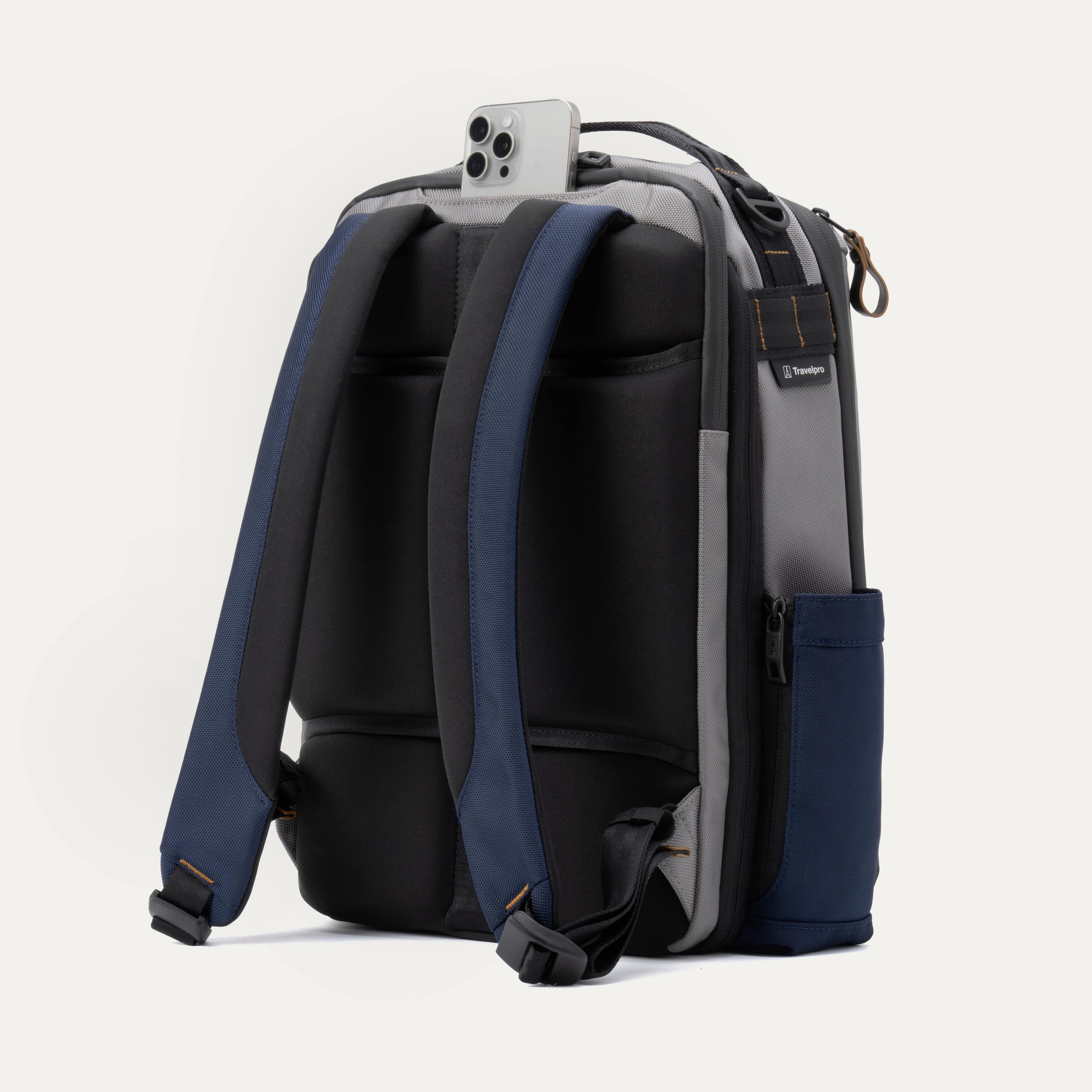 Rear view of the Travelpro Altitude Slim Expandable Laptop Backpack 20-24L in Stellar Navy and Grey, showing the ergonomic airflow back panel, adjustable shoulder straps, and a quick-access top pocket holding a smartphone.