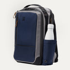 Side view of the Travelpro Altitude Slim Expandable Laptop Backpack 20-24L in Stellar Navy and Grey, highlighting the convenient side storage pocket holding a water bottle and the backpack's sleek, functional design.