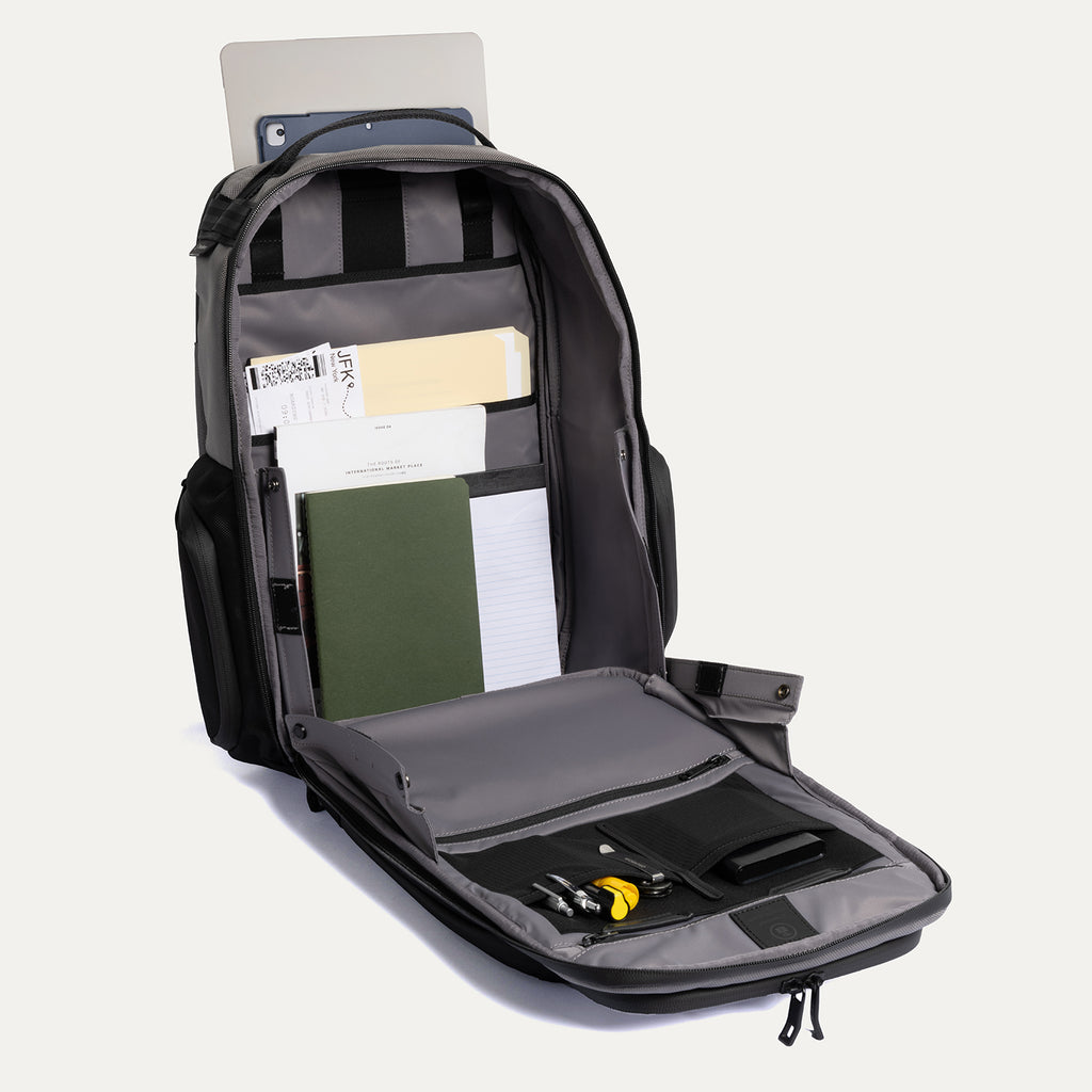 Open backpack with compartments and items on a light gray background