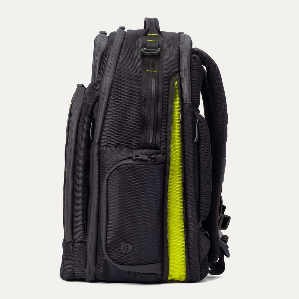 Side view of the Travelpro Altitude Large Backpack in Neon Shadow, showing black exterior with multiple zip pockets and partially open main compartment revealing neon yellow expansion panel against a light background.