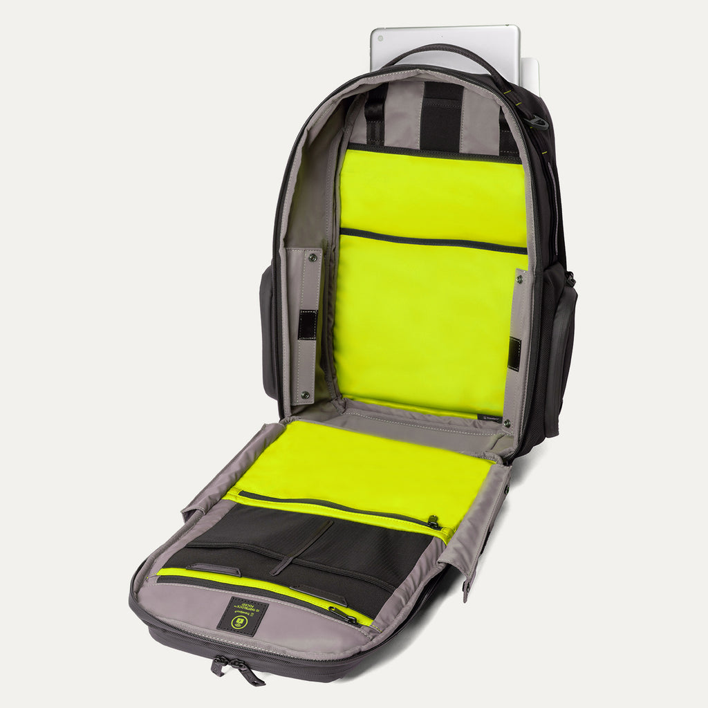 Front view of the Travelpro Altitude Large Backpack in Neon Shadow, showing fully open main compartment with neon yellow interior panels, gray lining, padded laptop sleeve, and organizer pockets against a light background.