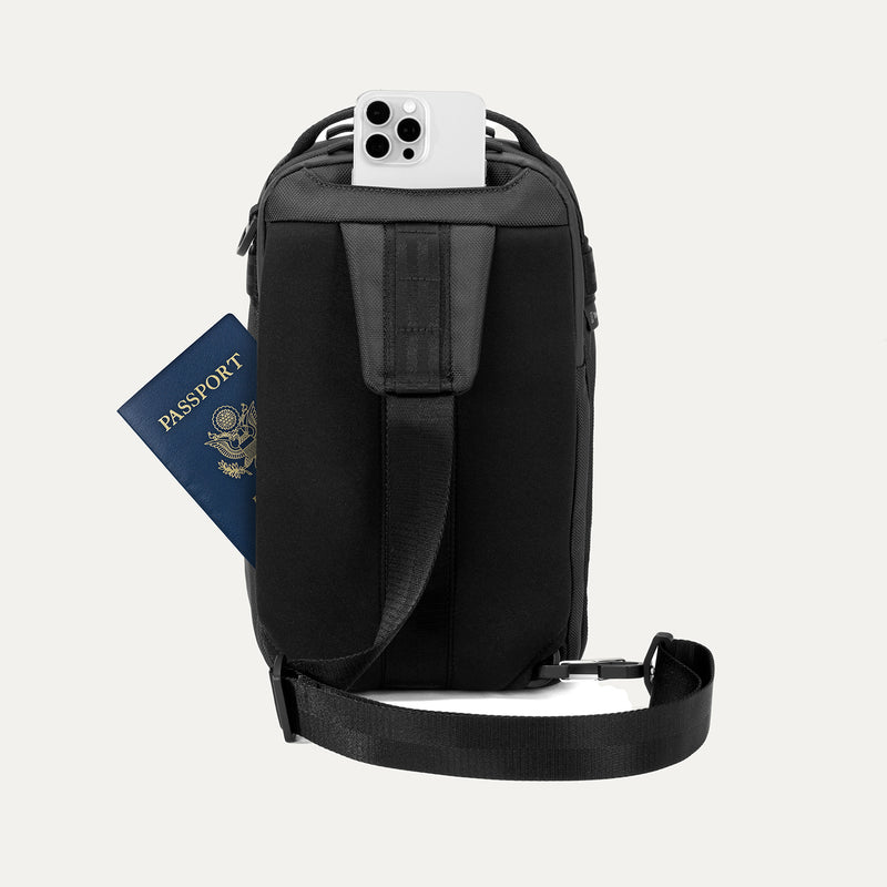 Rear view of Travelpro Altitude Crossbody 6L in Jet Black, showing rear slip pockets with phone and passport access.
