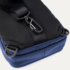Close-up rear view of the Travelpro Altitude Crossbody 6L in Aviator Navy, showing D-rings and rear clip attachment detail.

