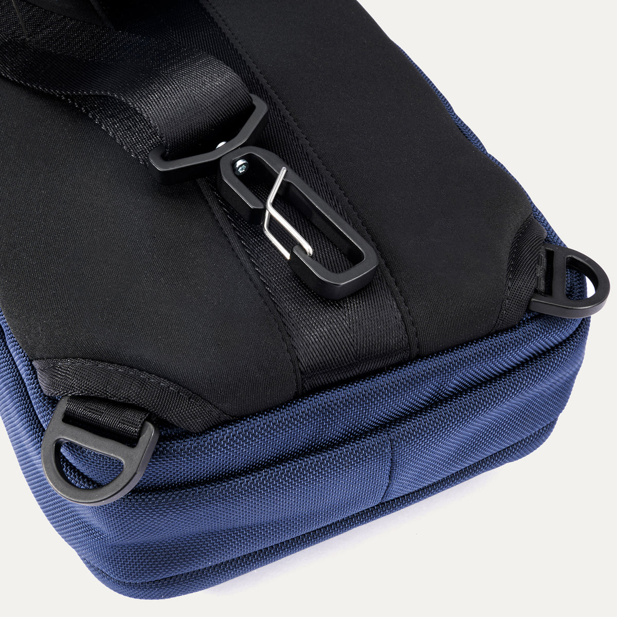 Close-up rear view of the Travelpro Altitude Crossbody 6L in Aviator Navy, showing D-rings and rear clip attachment detail.


