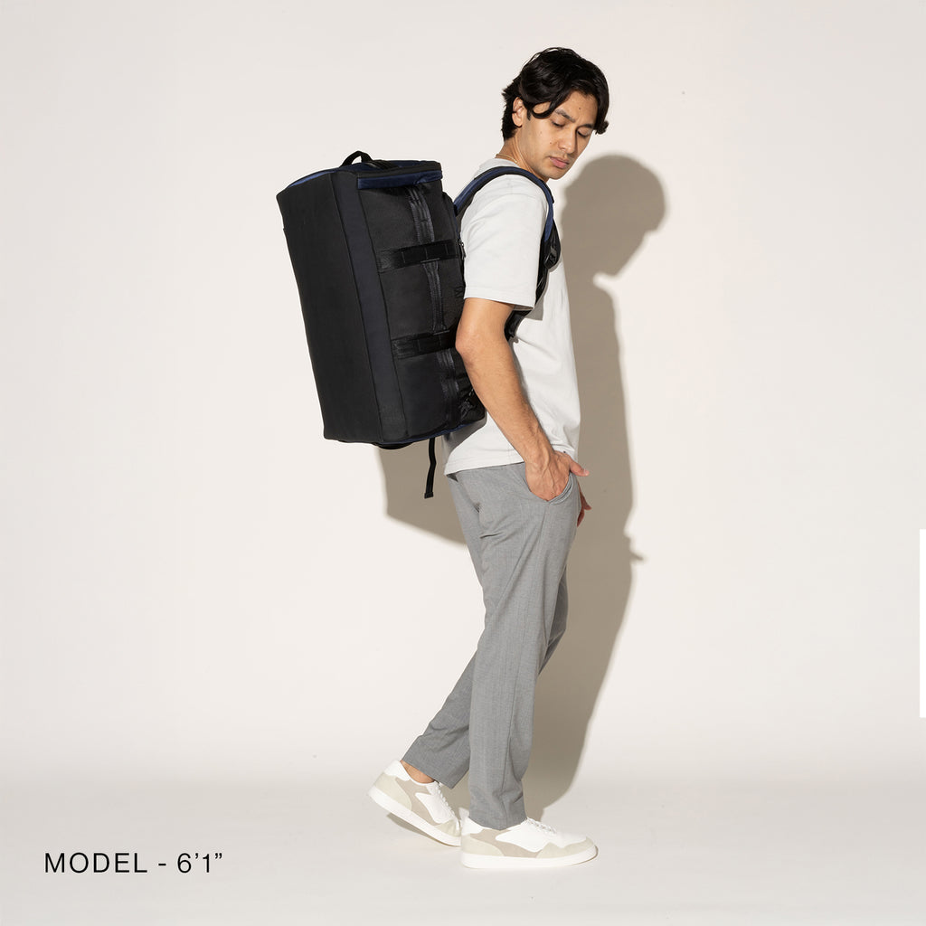 Person wearing a black convertible duffel on a white background