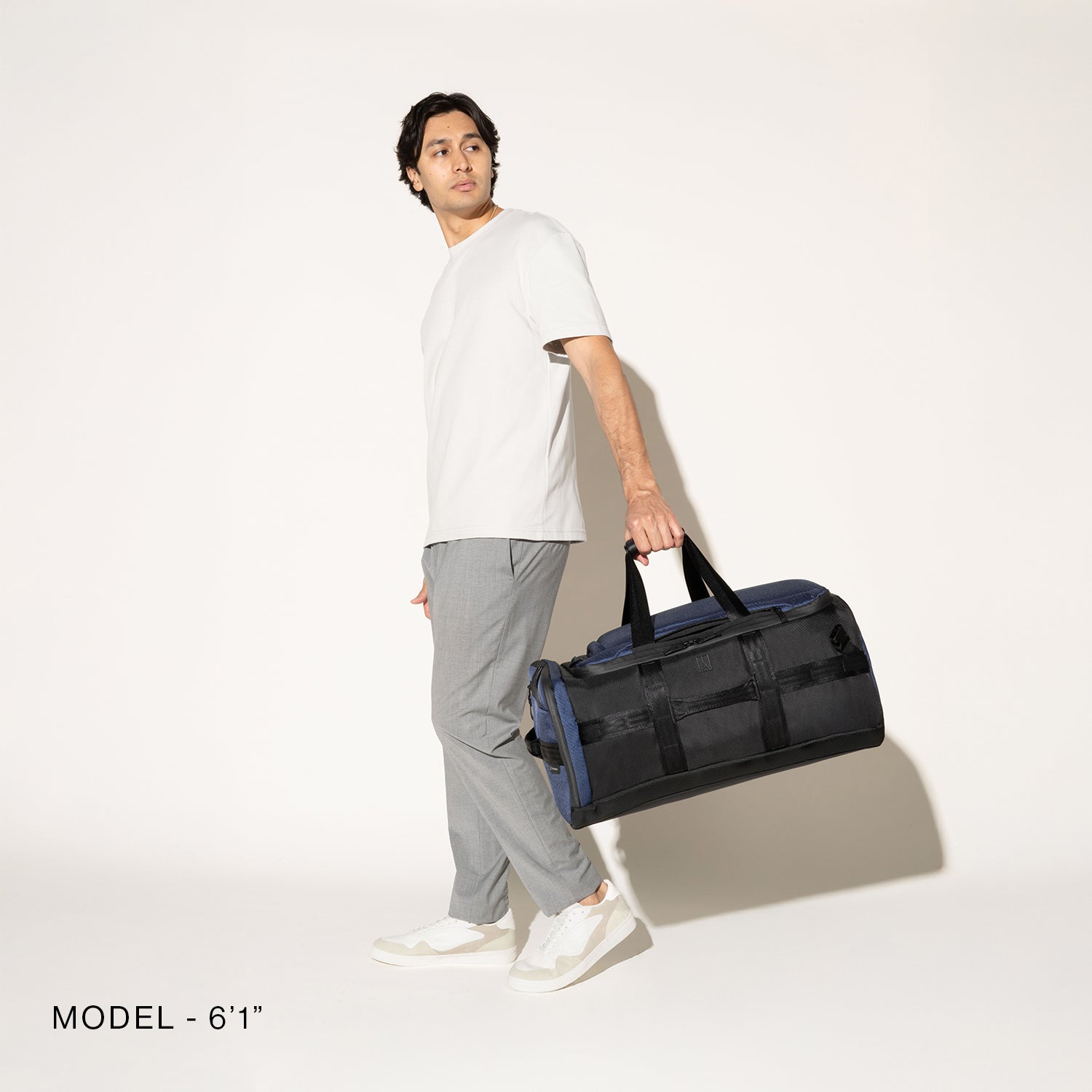 Person carrying a aviator navy convertible duffel on a white background