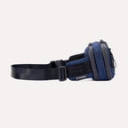 Side view of the Travelpro Altitude Sling 2L in Aviator Navy, showing Travelpro logo tab and adjustable buckle strap.
