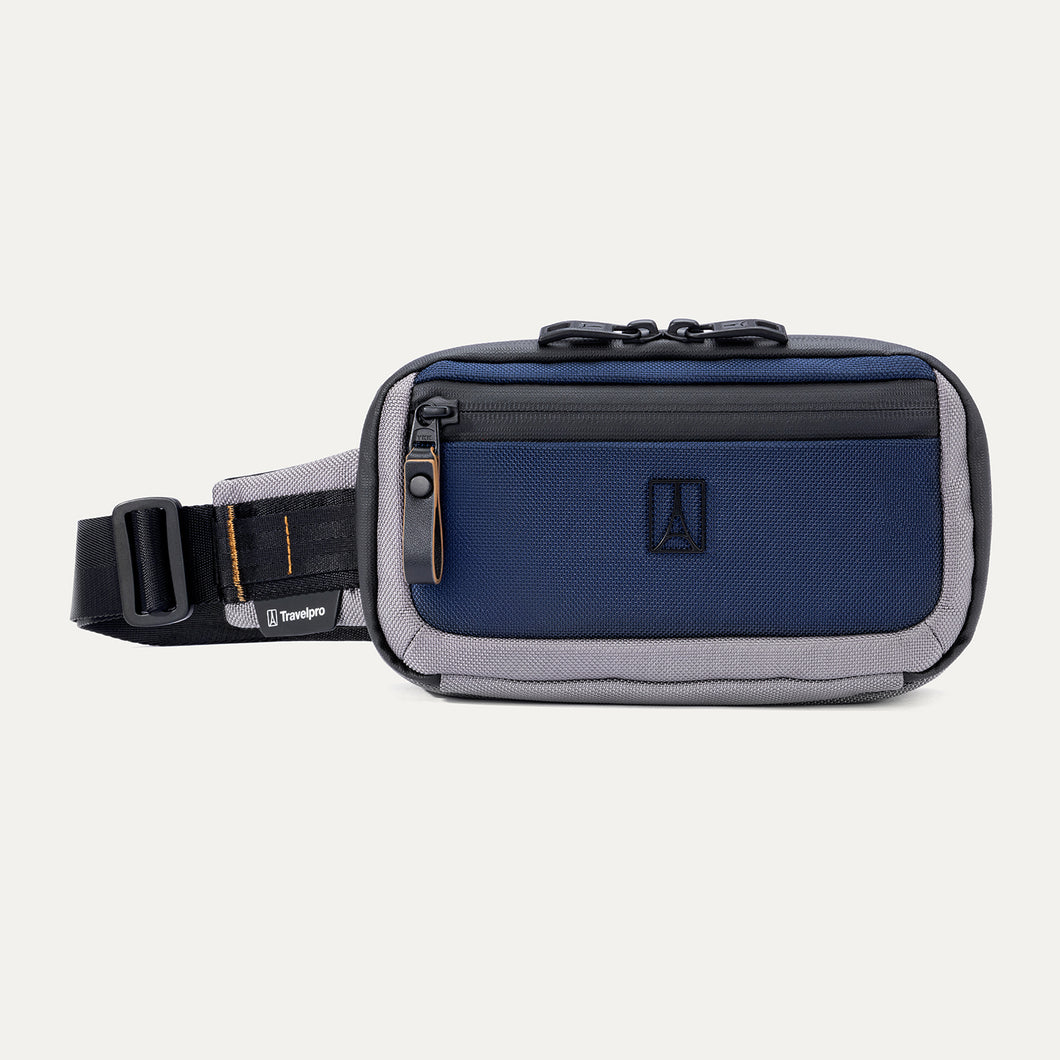 Front view of the Travelpro Altitude Sling 2L in Stellar Navy/Grey, showing front zip pocket, logo, and adjustable waist strap.
