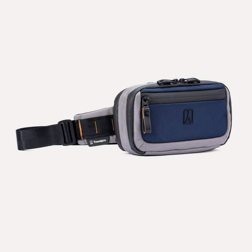 Angled front view of the Travelpro Altitude Sling 2L in Stellar Navy/Grey, featuring a front zip pocket and adjustable buckle strap.
