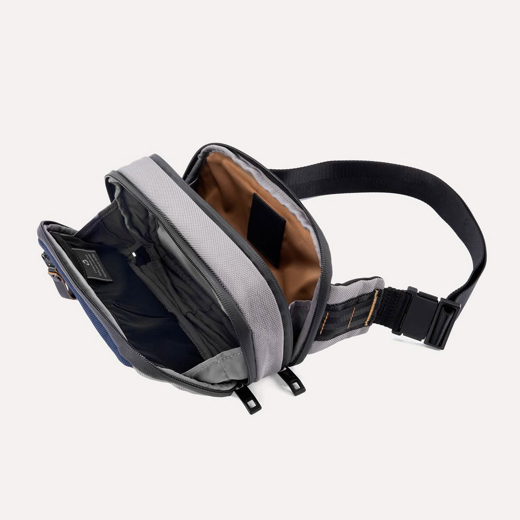 Interior view of the Travelpro Altitude Sling 2L in Stellar Navy/Grey, showing dual compartments with buckle strap.
