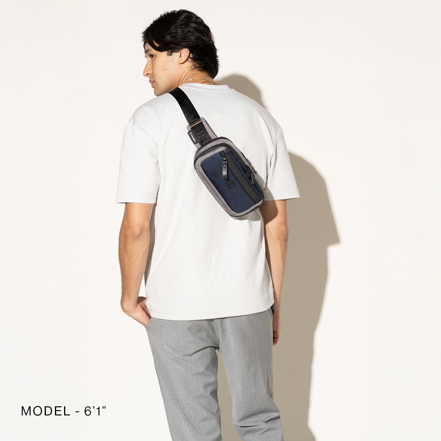 Person wearing a stellar navy sling over the shoulder on a white background