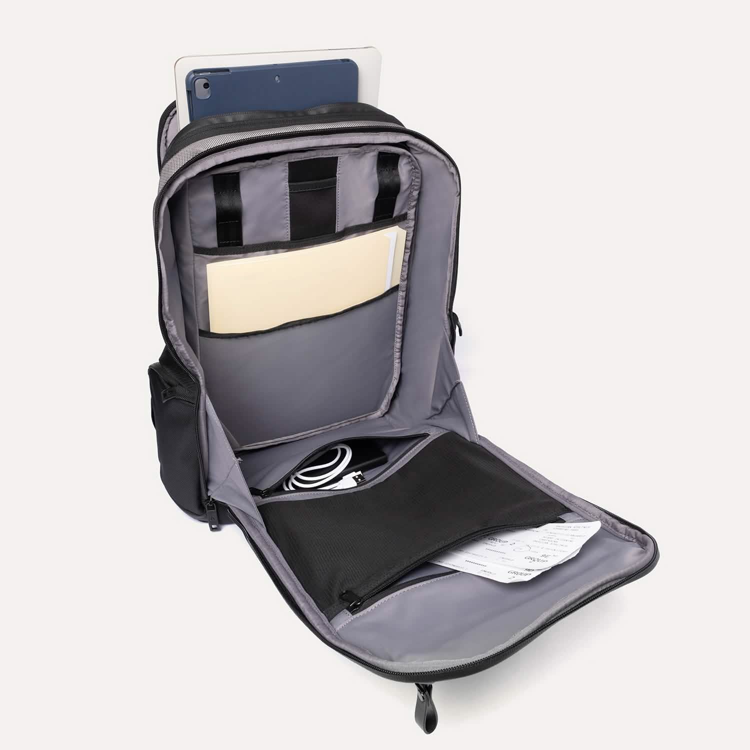 Gray backpack with compartments containing a tablet, notebook, and other items on a white background