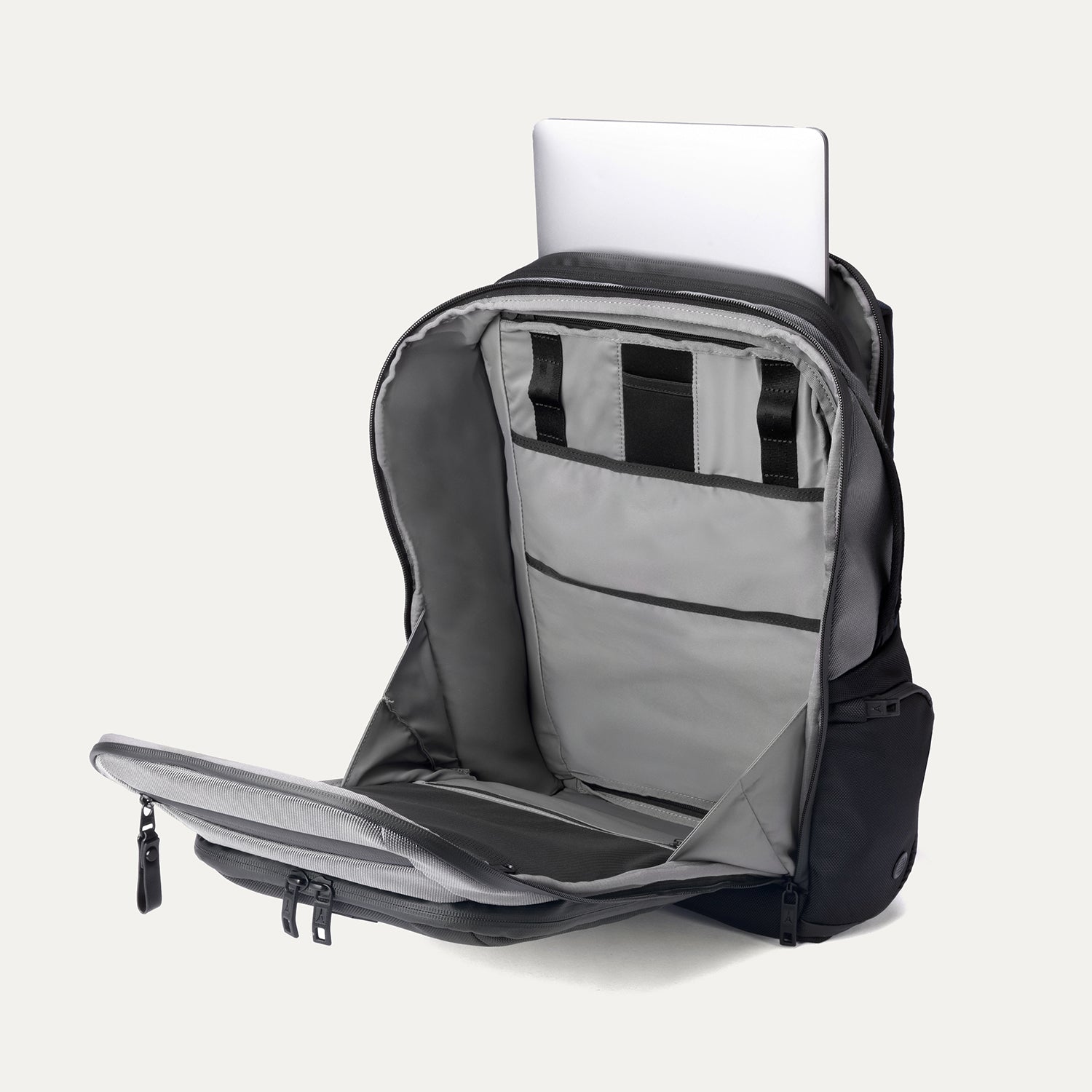 Interior view of Travelpro Altitude All-Purpose Laptop Backpack in Falcon Grey, with laptop partially in padded sleeve and multiple organizer pockets.
