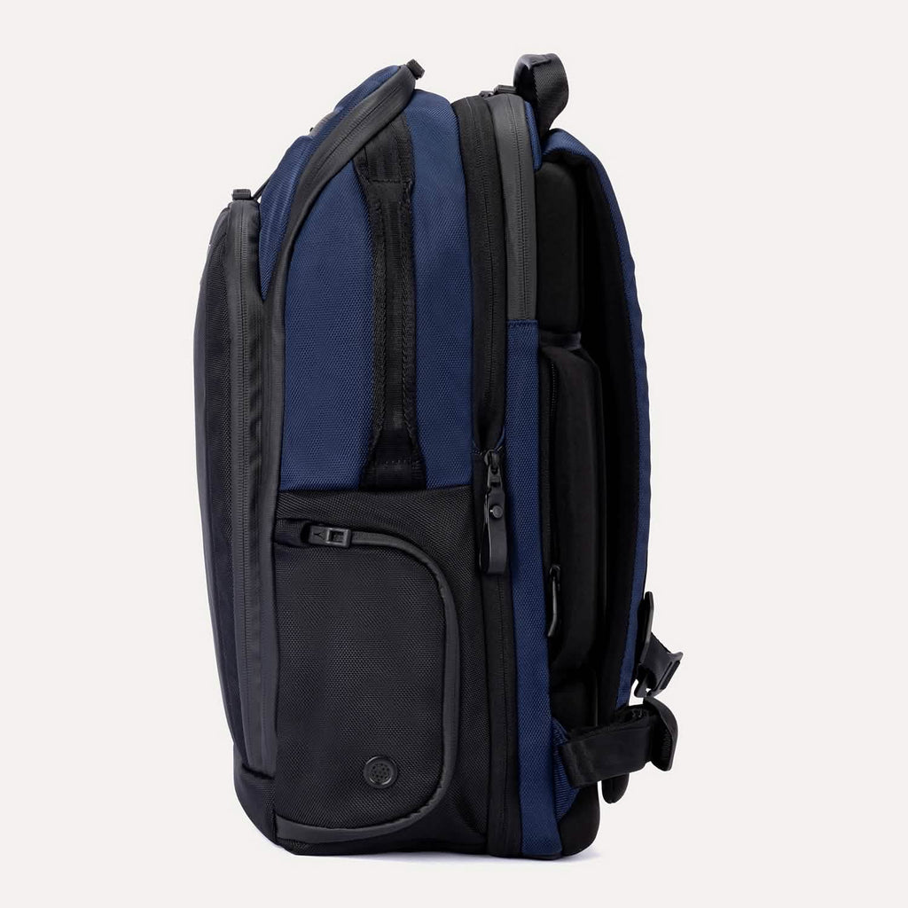 Side view of Travelpro Altitude All-Purpose Laptop Backpack in Aviator Navy, showing side-access pocket and padded back panel.
