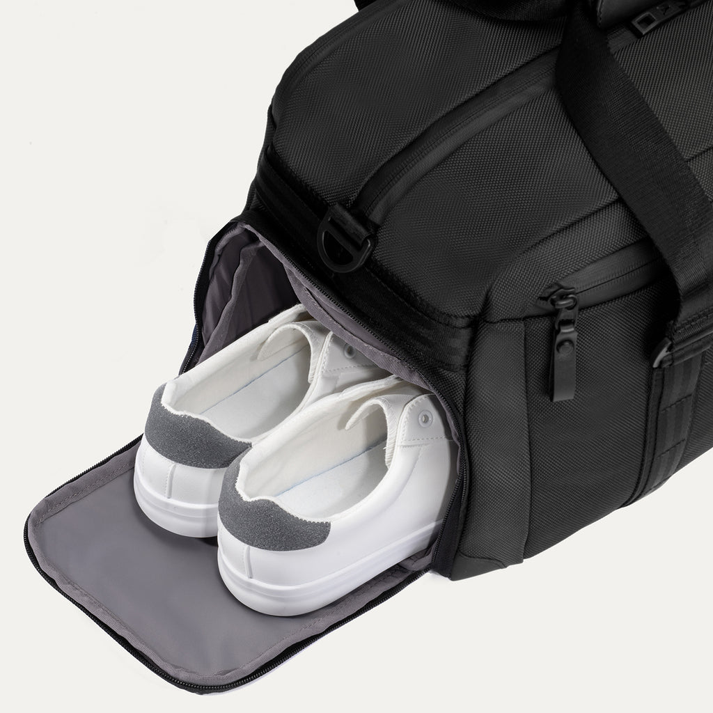 Travelpro Altitude Day-to-Day Duffel in Jet Black, showing open side compartment with shoes stored inside.
