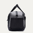 Side view of the Travelpro Altitude Day-to-Day Duffel in Falcon Grey, showing the adjustable shoulder strap and end pocket.
