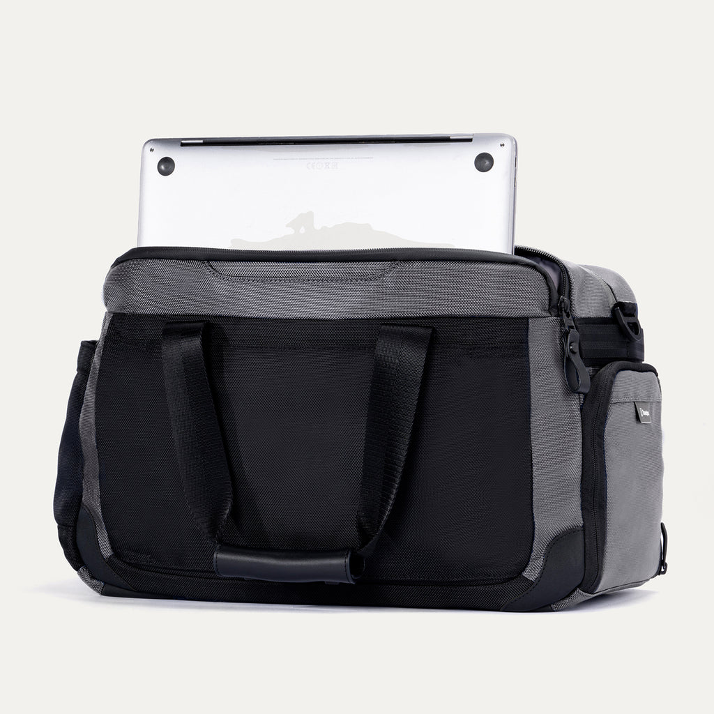 Rear view of the Travelpro Altitude Day-to-Day Duffel in Falcon Grey, showing laptop partially stowed in padded sleeve.
