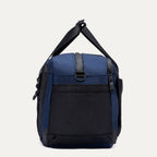 Side view of the Travelpro Altitude Day-to-Day Duffel in Aviator Navy, highlighting the zip pocket and adjustable shoulder strap.
