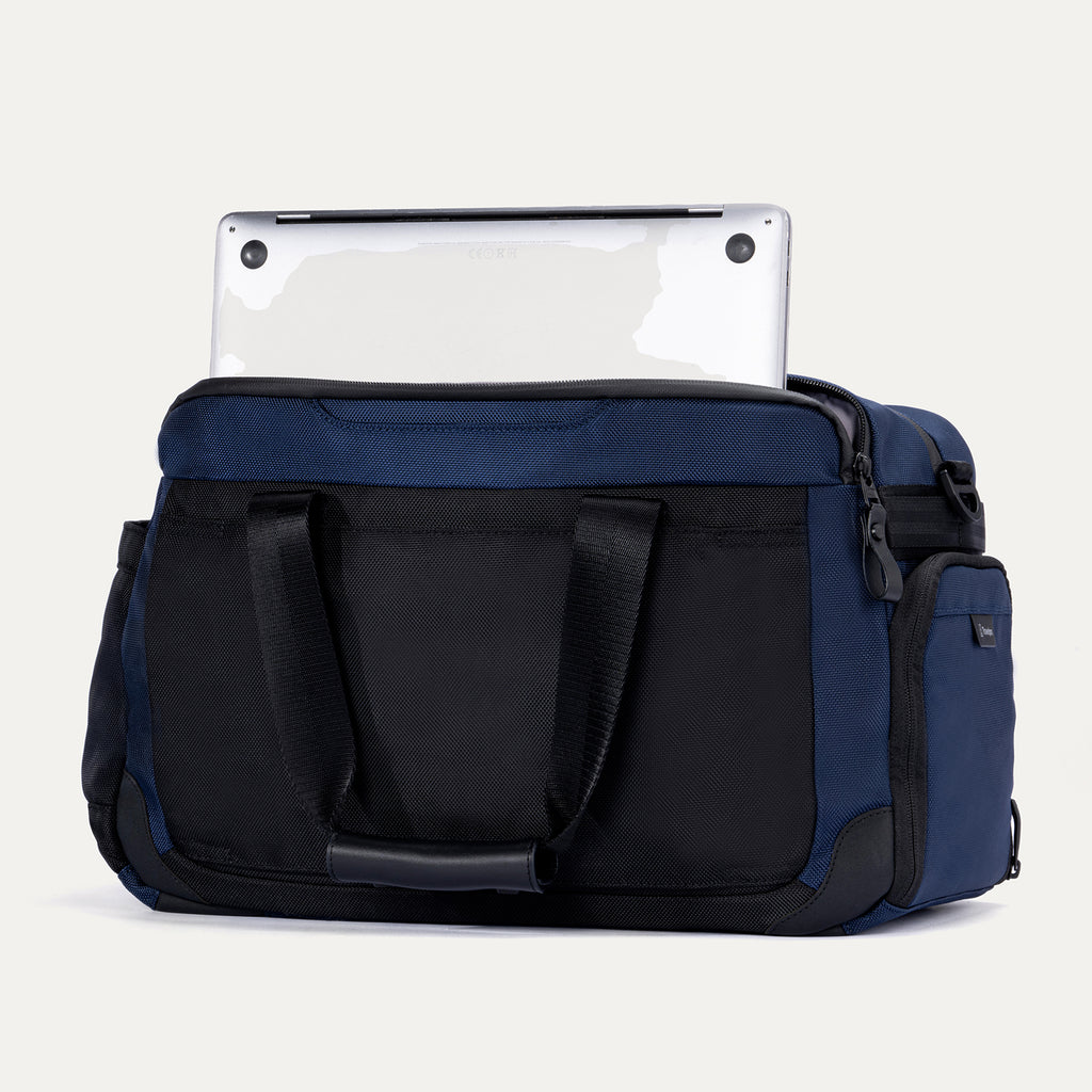 Rear view of the Travelpro Altitude Day-to-Day Duffel in Aviator Navy, showing a laptop partially stored in the padded sleeve.


