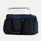 Rear view of the Travelpro Altitude Day-to-Day Duffel in Aviator Navy, showing a laptop partially stored in the padded sleeve.


