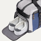  Travelpro Altitude Day-to-Day Duffel in Stellar Navy/Grey, with shoe compartment open and holding white sneakers.
