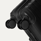 Black suitcase with wheels on a light gray background