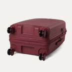 Maroon suitcase with wheels on a light gray background