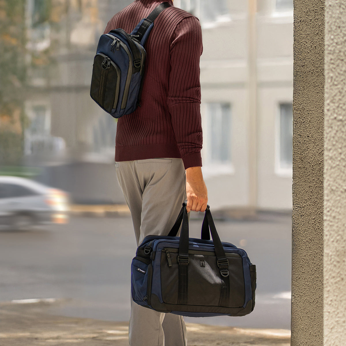 Person holding a black and blue duffel bag on a city street