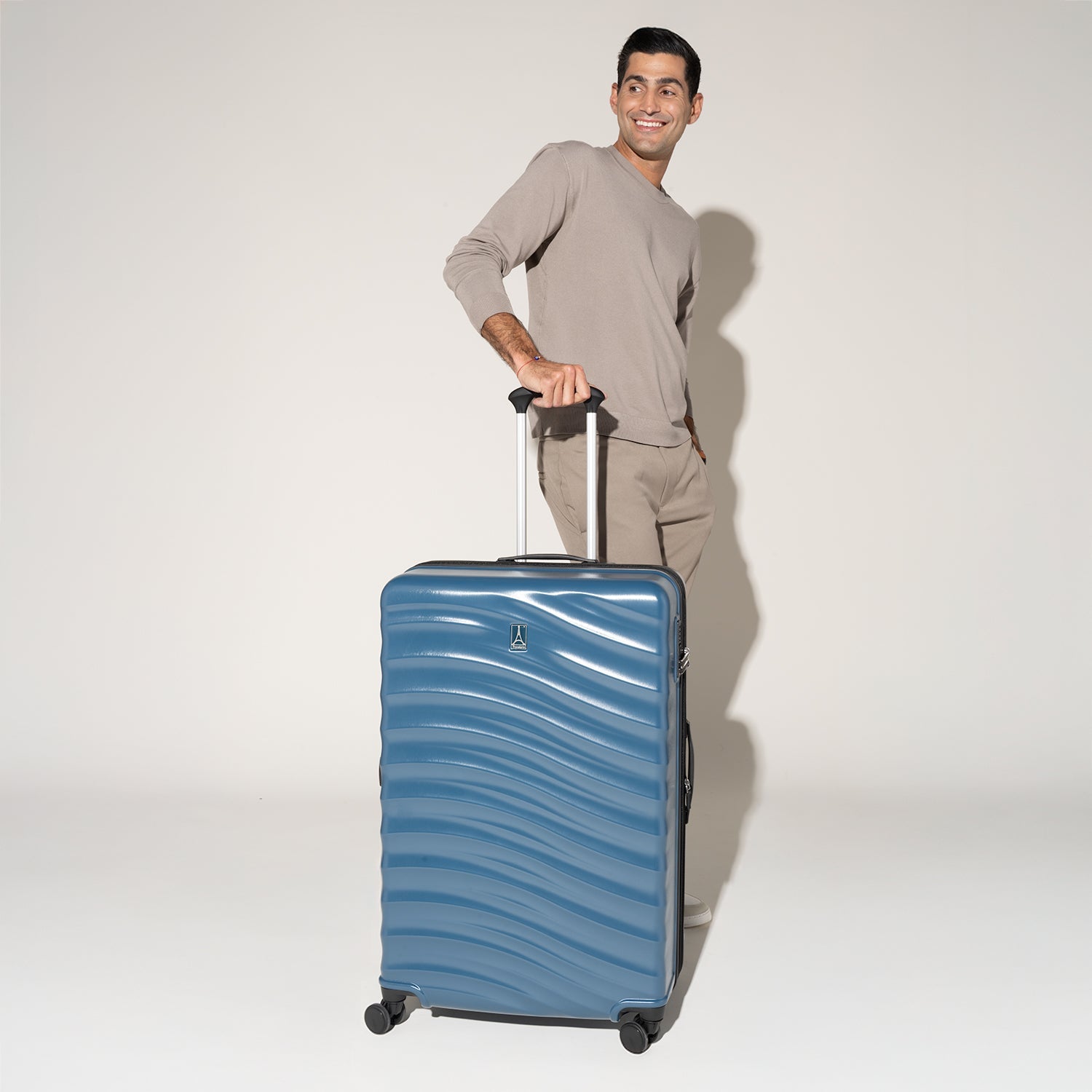Man standing with the Travelpro Maxlite Air V2 in Teal, upright on 360° Spinner Wheels with handle extended.
