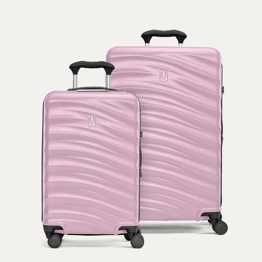 A set of two pink hardside spinner suitcases, one carry-on size and one medium check-in size, with a textured surface, integrated handles, and wheels.