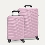 A set of two pink hardside spinner suitcases, one carry-on size and one medium check-in size, with a textured surface, integrated handles, and wheels.