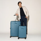 Man standing beside the Travelpro Maxlite Air V2 Carry-On and Large Check-In Set in Teal, featuring textured shell and 360° Spinner Wheels.