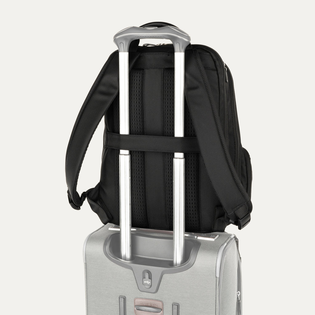 Black backpack hanging on top of a suitcase on a white background
