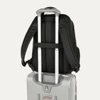 Black backpack hanging on top of a suitcase on a white background