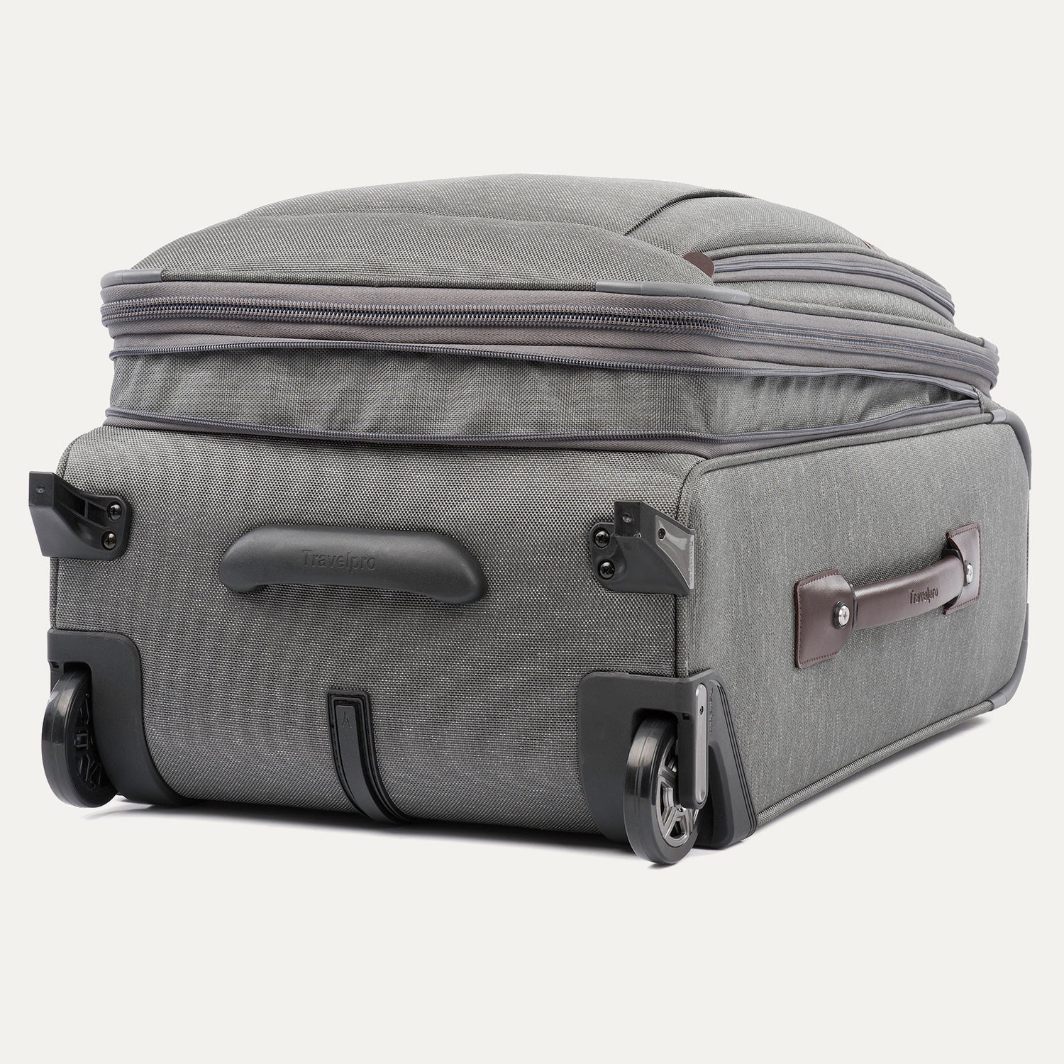 Gray suitcase with wheels laying on the ground expanded on a white background