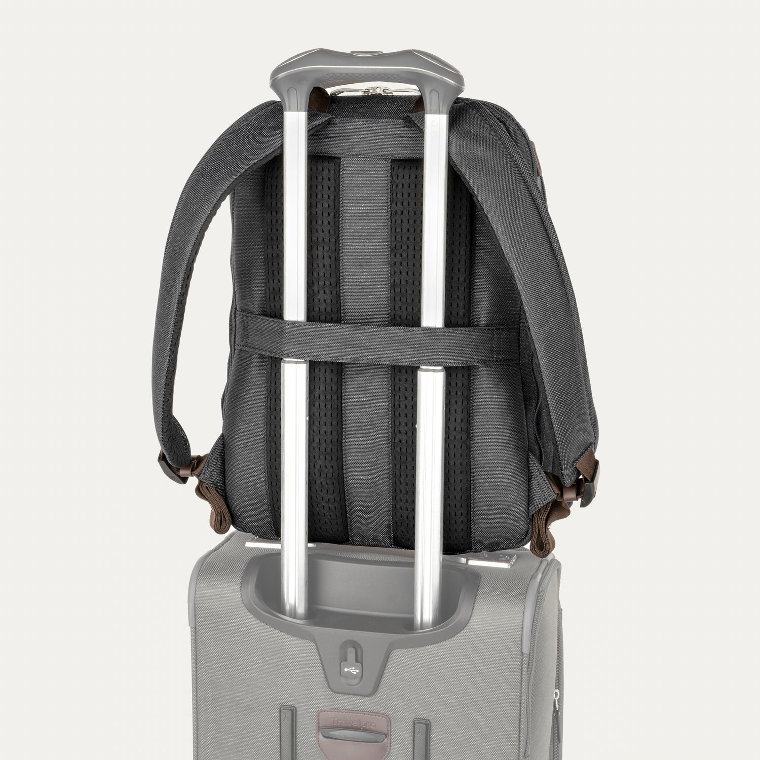 Backpack with rolling handle attached to a suitcase on a light gray background