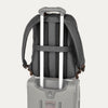 Backpack with rolling handle attached to a suitcase on a light gray background