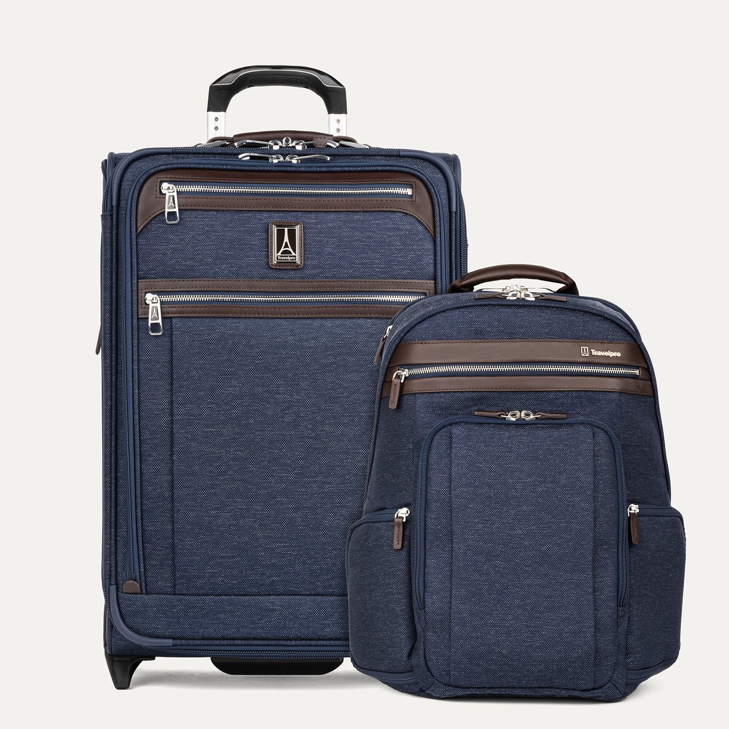 A navy carry on 2 wheel suitcase and a navy backpack with brown accents on a light gray background