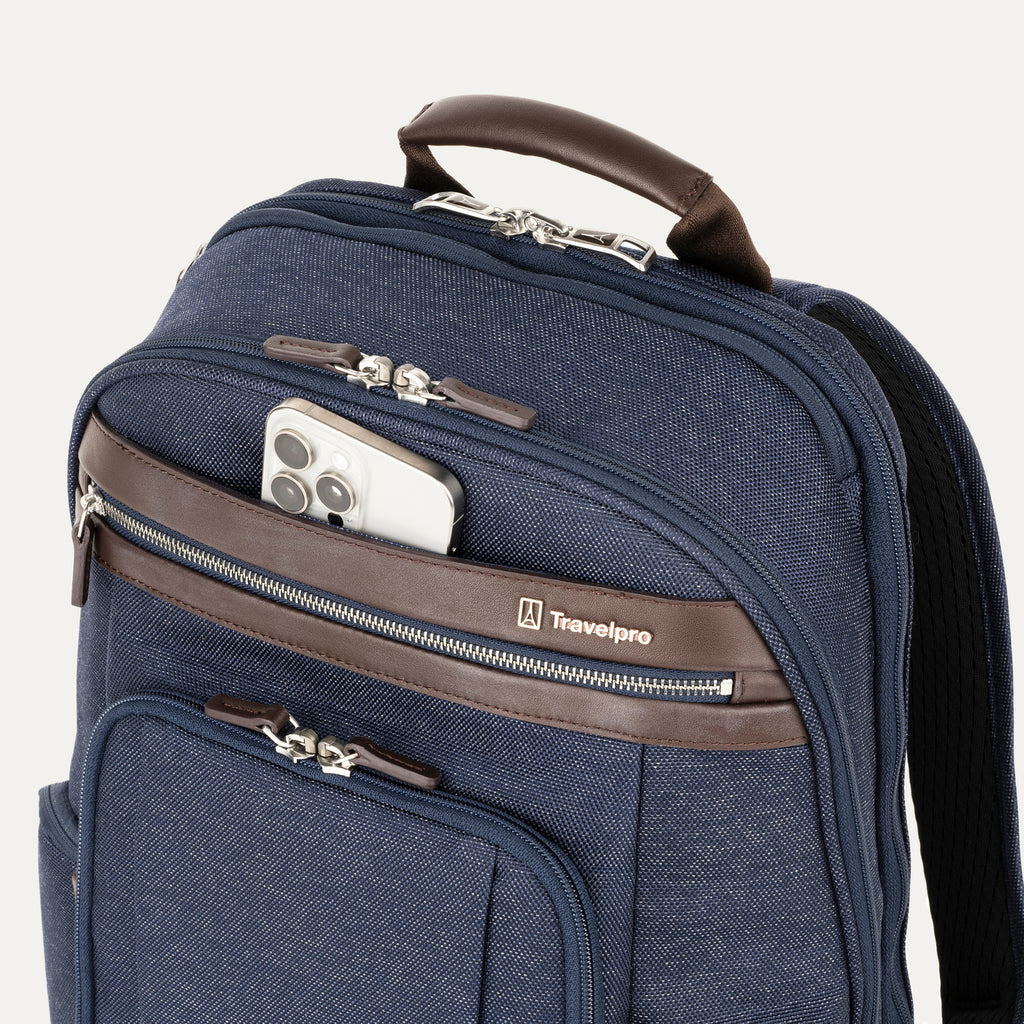 Blue backpack with brown accents with a cellphone sticking out of front pocket and a visible Travelpack logo on a white background