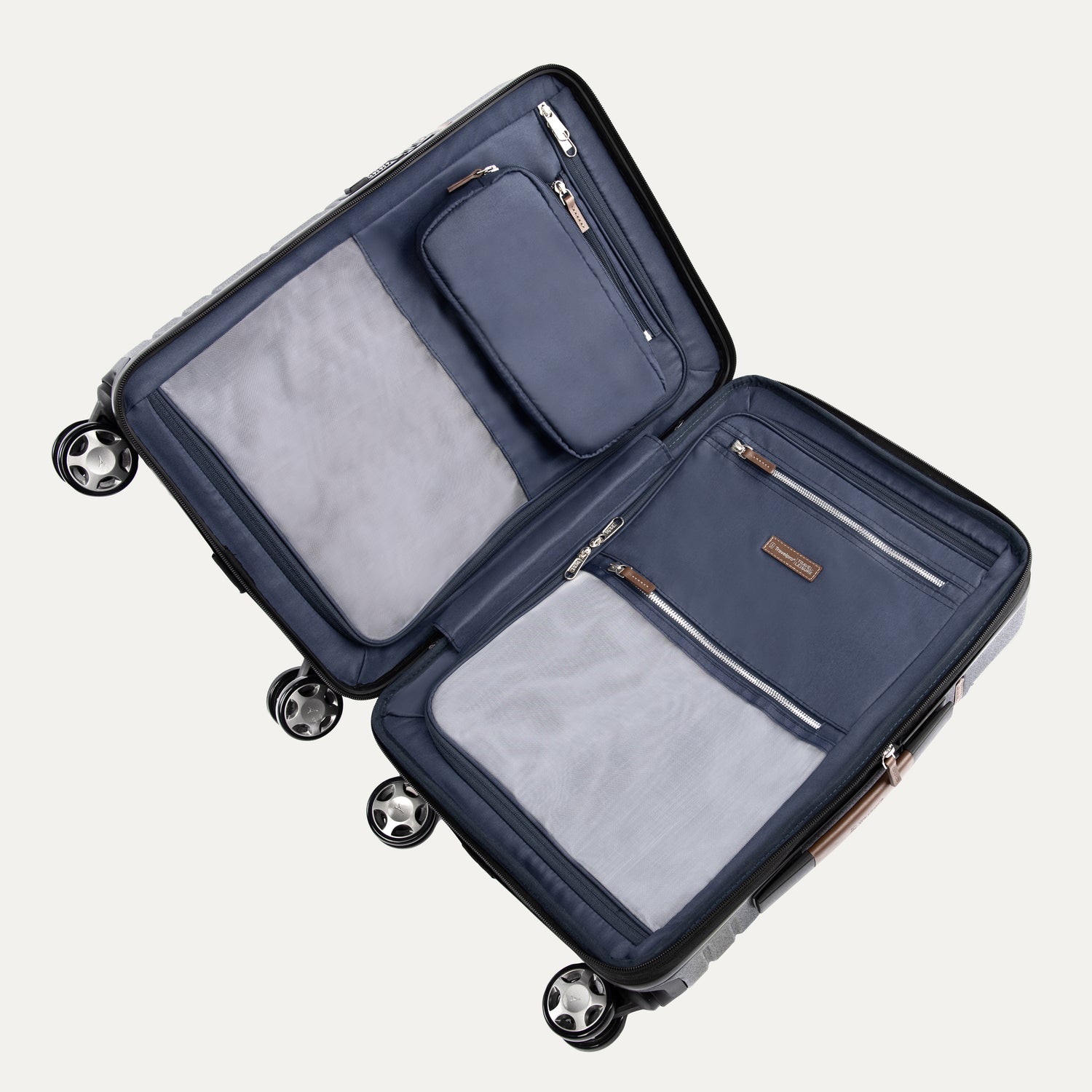interior view of the open monaco blue travelpro x travel plus leisure hardshell spinner suitcase lying flat, showcasing its fully lined navy blue compartments, zippered privacy separator panels with built-in mesh and solid organizing pockets, and elegant brown leather zipper pulls.