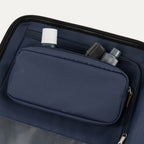 close-up interior view of the monaco blue travelpro x travel plus leisure suitcase compartment, highlighting a built-in zippered organizer pocket holding travel-sized toiletry bottles, featuring premium navy lining and an elegant brown leather zipper pull.