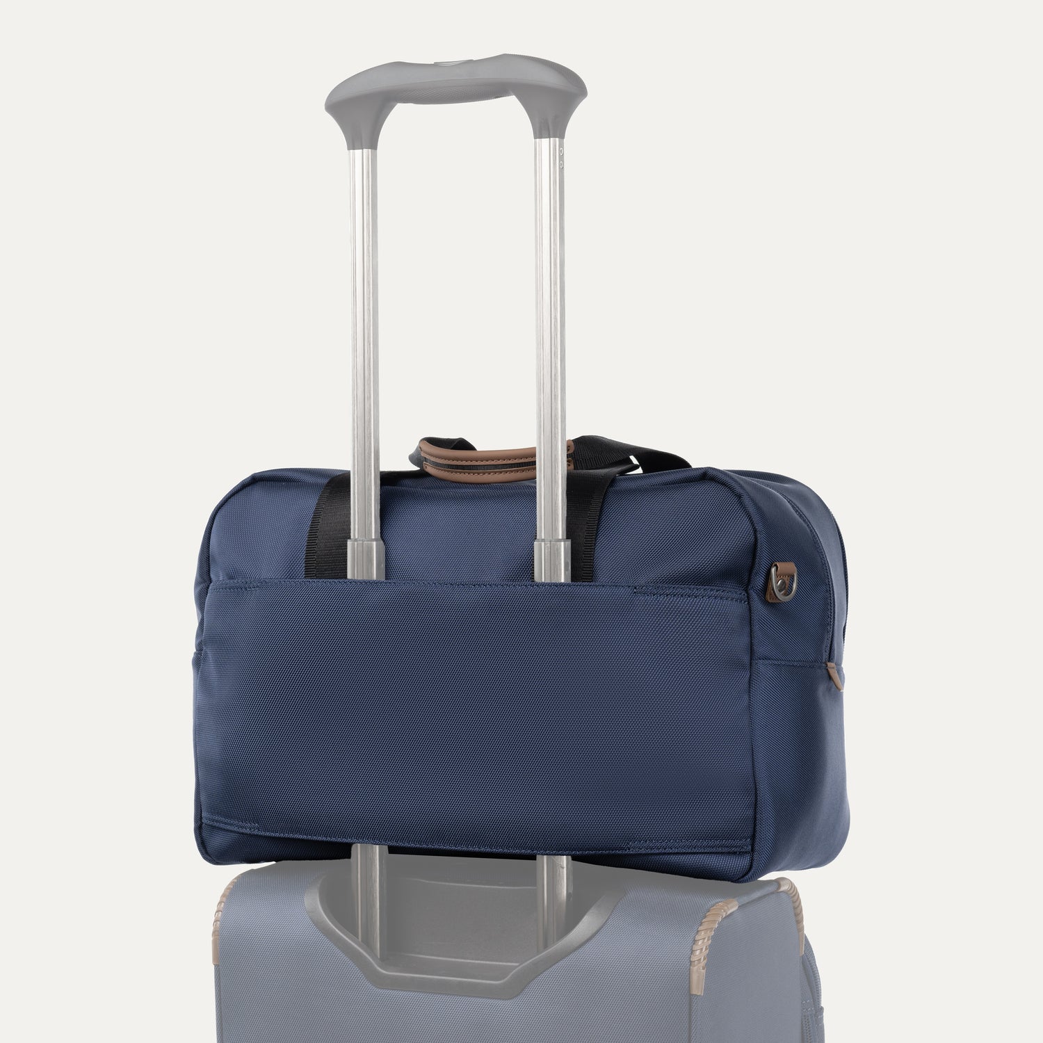 Blue tote bag stacked on top of luggage on a white background