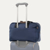 Blue tote bag stacked on top of luggage on a white background