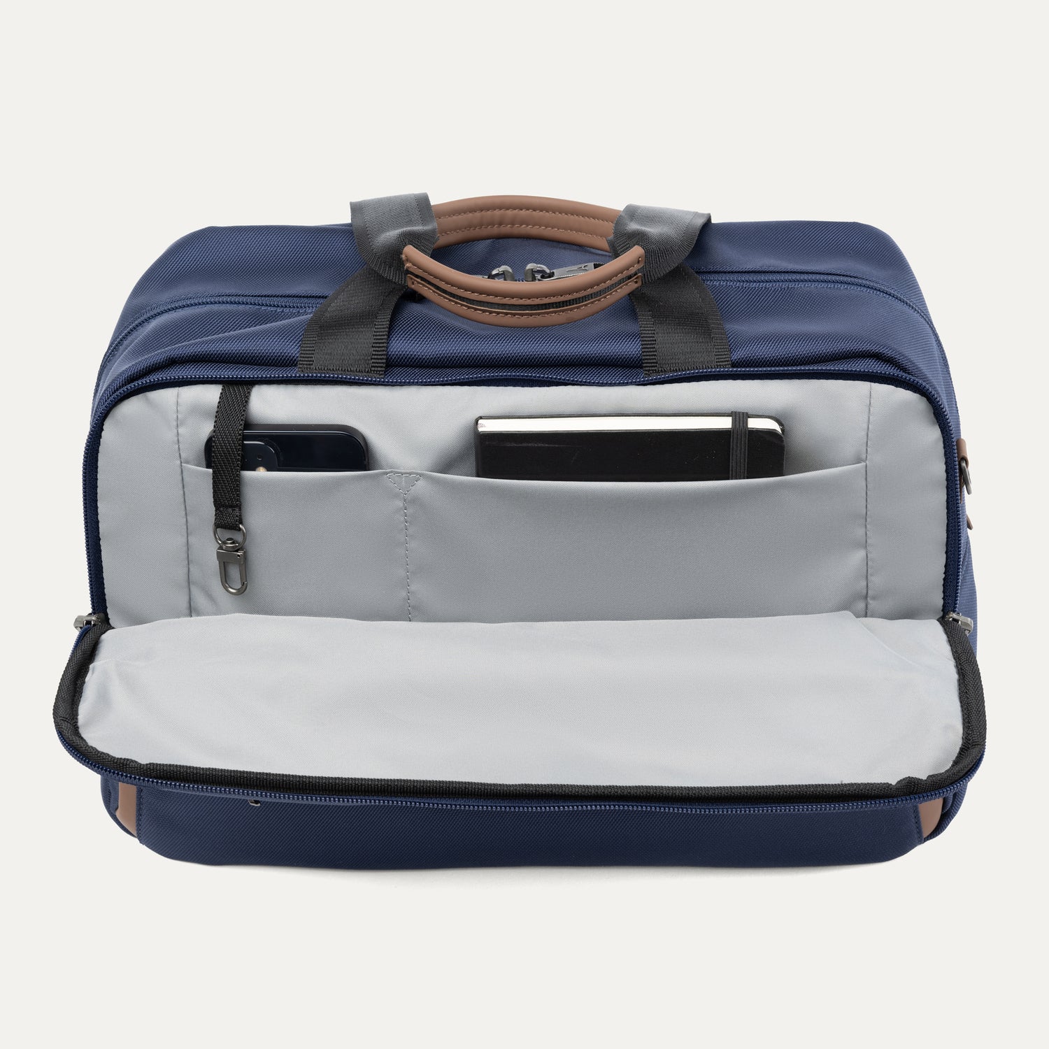 Blue tote bag showing front open compartment  with phone and notepad on a light gray background
