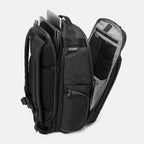 Black backpack with tech compartments open, showing laptop and tablet inside on a white background
