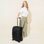 A person pulling a black carry-on spinner luggage with telescopic handle.