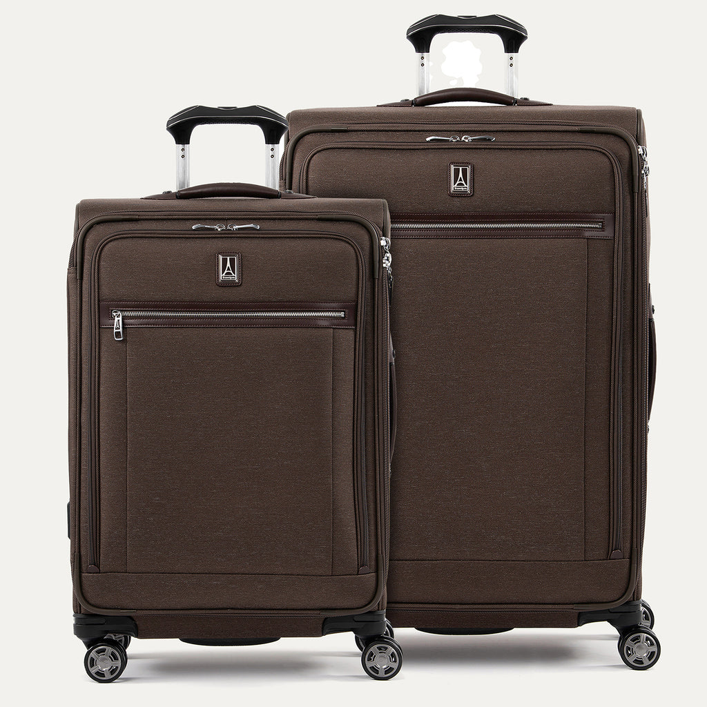 A set of two brown suitcases with spinner wheels, a smaller one in front and a larger one behind, both with the Travelpro logo.